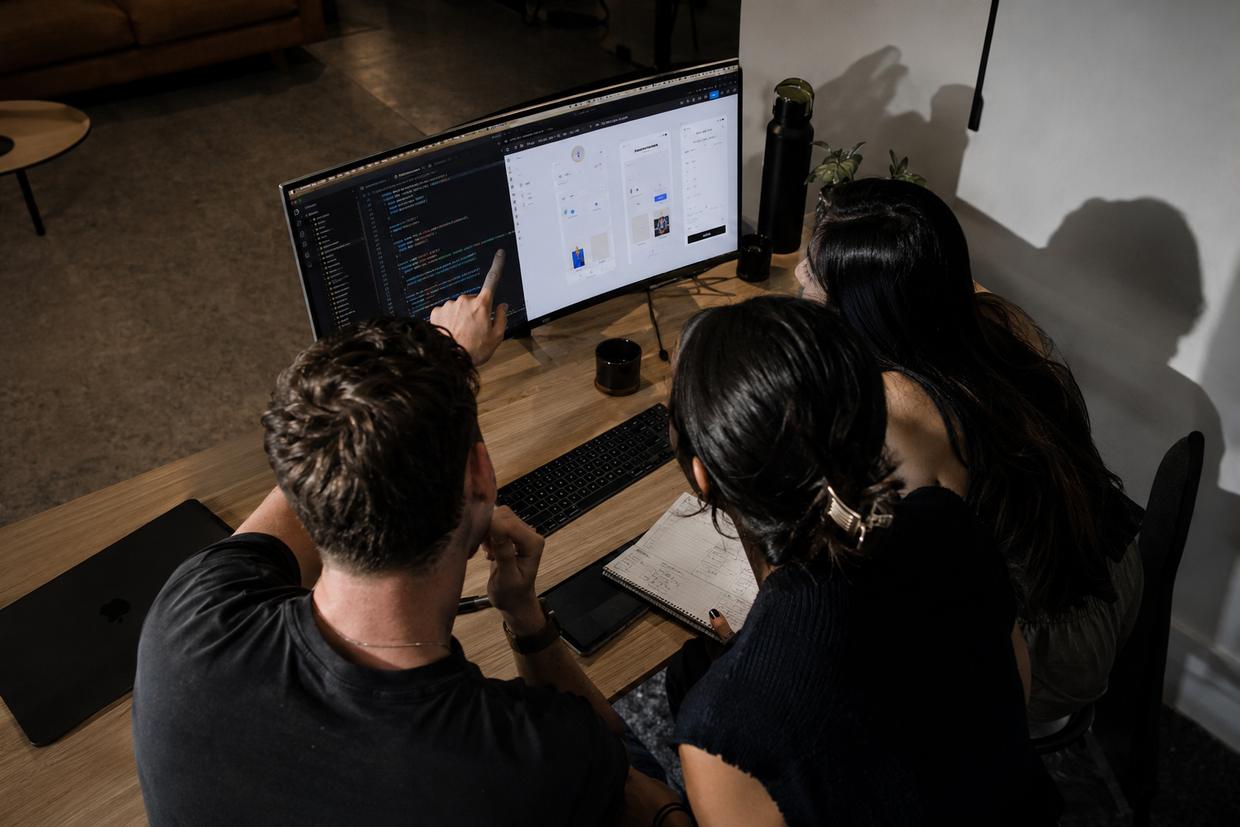 Two designers and an engineer reviewing an interface together at a shared desk